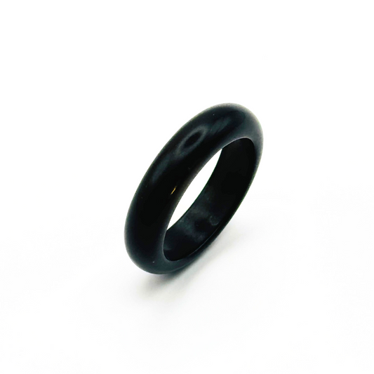 A polished, rounded edge black gemstone ring on a white background.
