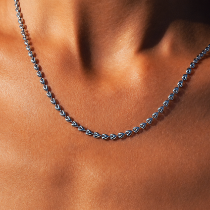 A close-up of a silver heart link chain necklace worn on a person's neck.