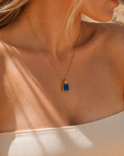 Gold necklace with a blue pendant on a person's neck